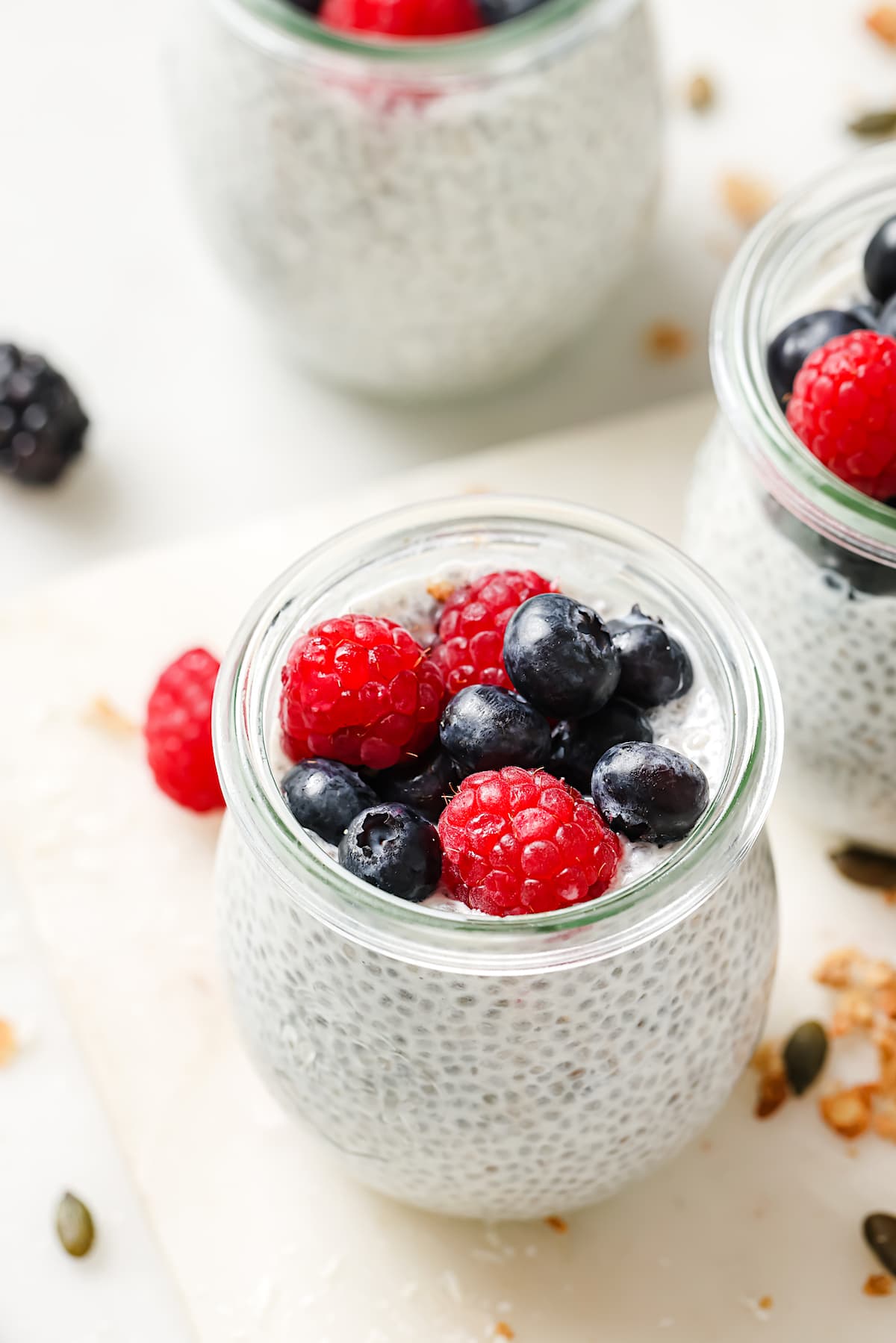 Berry chia pudding in glass jars topped with raspberries and blueberries