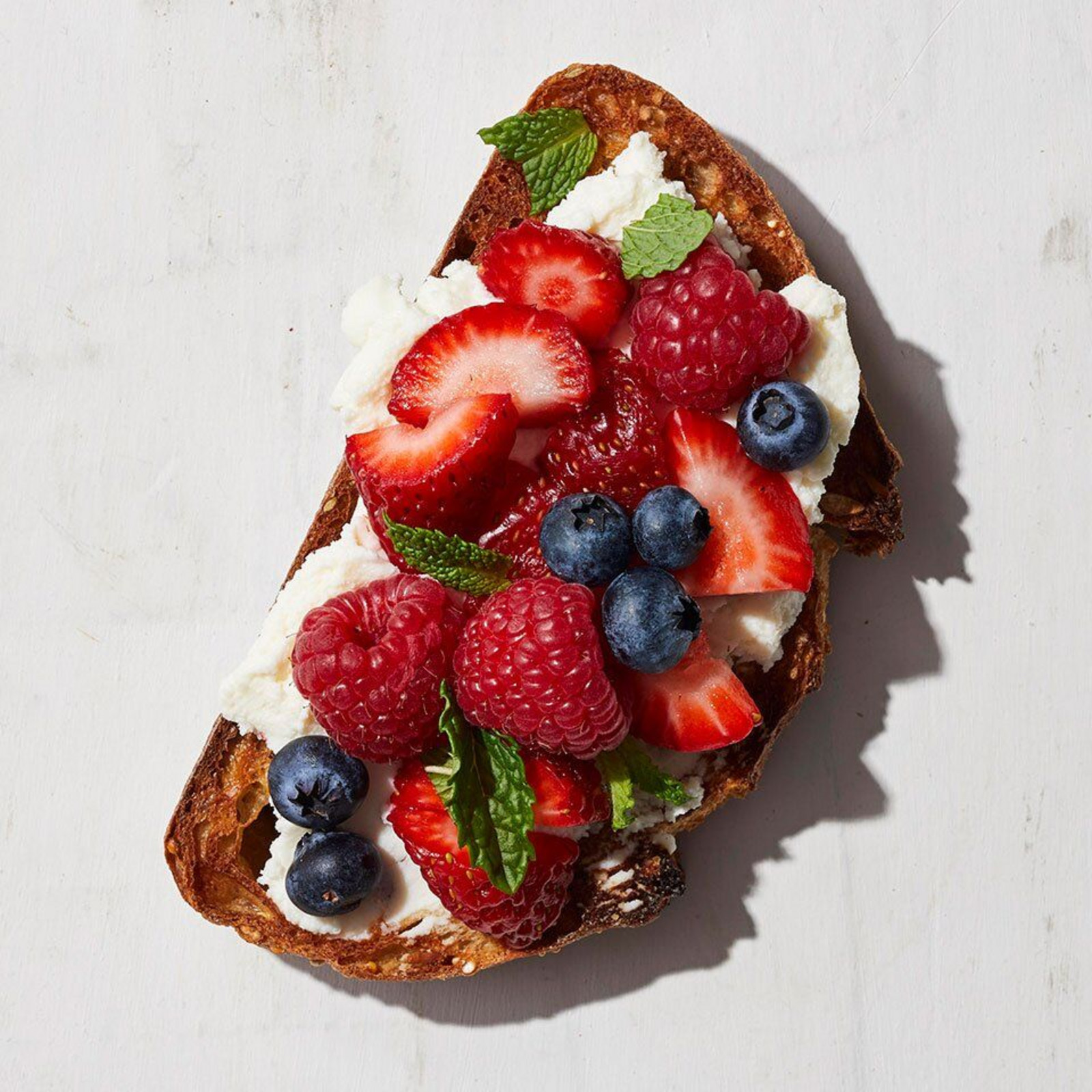Sourdough toast topped with cottage cheese, strawberries, raspberries, and blueberries